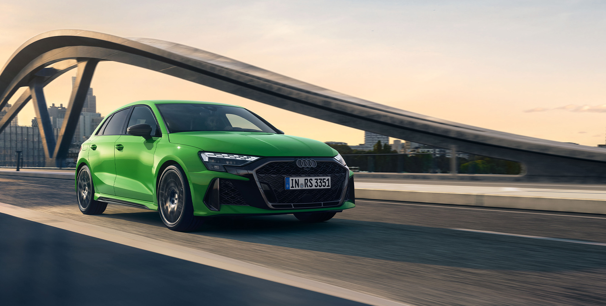 Ein gr&uuml;ner Audi RS 3 Sportback in Front-Seitenansicht der grade &uuml;ber eine Br&uuml;cke f&auml;hrt