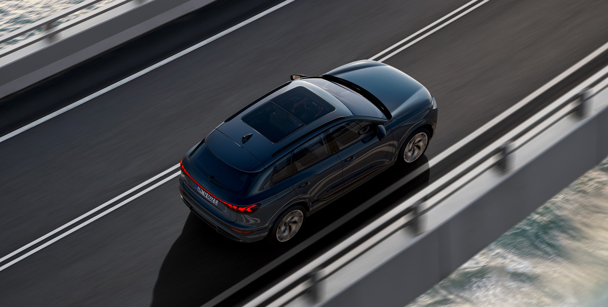 Ein fahrender Audi Q6 SUV e-tron in seitlicher Vogelperspektive