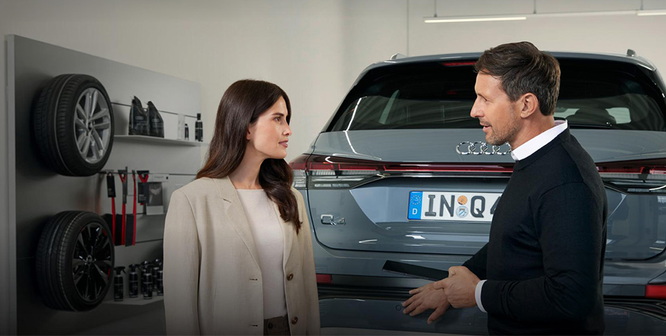 Zwei Personen stehen vor einem Audi Q4 und unterhalten sich.