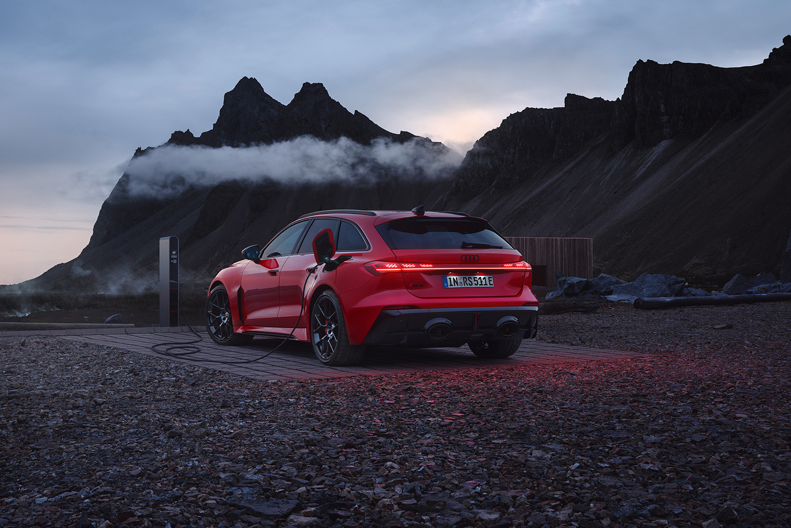 Audi RS 5 Avant, rot, Heckansicht, l&auml;dt an Lades&auml;ule in rauer Bergwelt