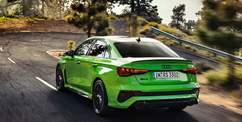 Eine grüne Audi RS3 Limousine von Hinten in der Dreiviertelansicht